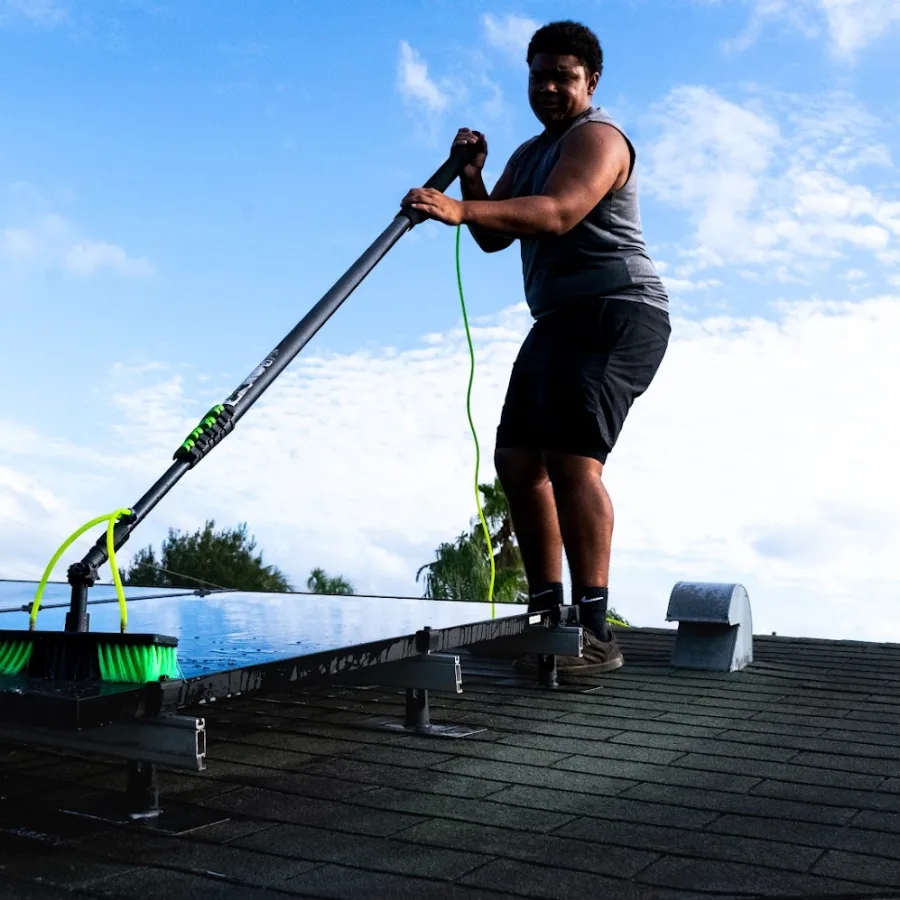 Ryan March, owner of Solaris Cleaning Company, soft-brushing a rooftop solar array